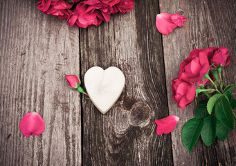 Heart and red roses on wooden table. Vintage Valentine Floral background. Toned image in retro style.