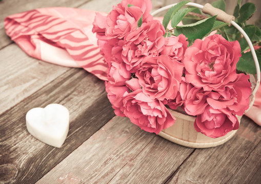 Flowers. Bouquet of red roses with Heart of marble on wooden table. Vintage Valentine Floral background. Toned image in retro style.