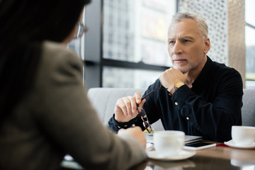selective focus of businessman holding glasses and talking with businesswoman in cafe