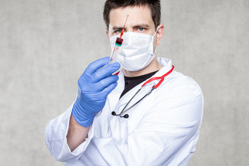 doctor holds a syringe in his hand filled with red liquid, concept of blood sampling or vaccine