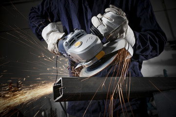 Close up on a man hold an angle grinder to cut an iron with sparks - obrazy, fototapety, plakaty