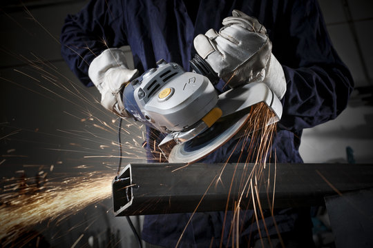 Close up on a man hold an angle grinder to cut an iron with sparks