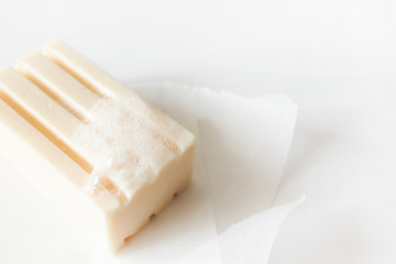 Close-up foam bubbles soap bar with selective focus on paper on white background. Health care, body care and hygiene