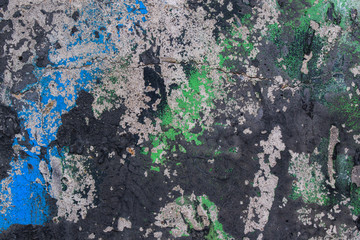 Concrete wall with old paint. Colors - green, blue, black, gray. Cracks and stones.