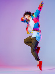 Guy dancing contemporary dance in studio. Neon light grey background. Acrobatic bboy dancer. Break dance lessons.