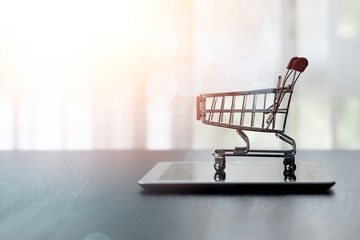 Shopping cart or trolley on tablet with sunlight. Online shopping concept.