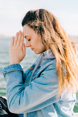 a young beautiful girl is sitting on a pier near the lake and doing meditation practice on a Sunny spring day