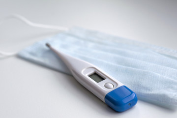 Thermometer on a medical mask in blue on a white background. Coronavirus Precautions Mask Protection.