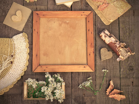 Clean old wooden frame mock-up and vintage objects on rustic wooden table. Vintage autumn mockup background. Mock up top view. Toned image in retro style.
