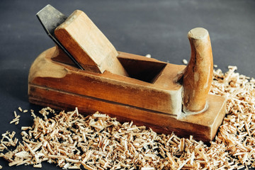 Old hand plane and wood shavings on black background. Old woodworking hand too on a black background. Copy, empty space for text