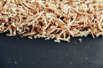 Wood shavings on black background. Background of fresh wood shavings. Copy, empty space for text