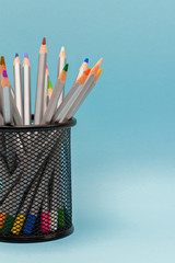 gray wooden pencils with colored rods in the stand on a blue background