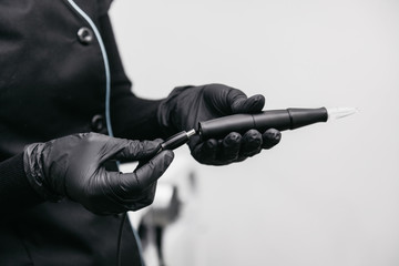 Beautician connects with a cord machines for permanent makeup
