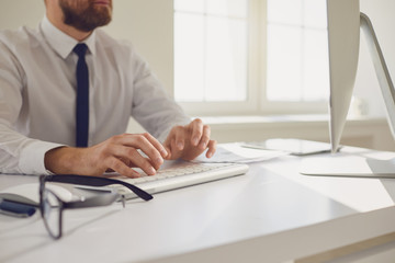 Work training online. Male hands of businessman tipping using keyboard on computer desk.