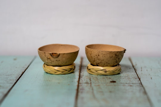 Two traditional "jicama" cups for drinking mezcal in Mexico, on their "rodete" stands. Cups made from the skin of the gourd fruit of a jicama tree. On a rustic vintage wood table painted green.