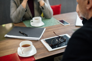 cropped view of businessman and businesswoman sitting at table in cafe