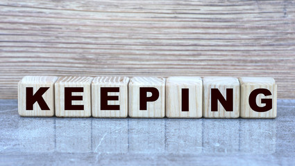 Fototapeta premium KEEPING , the word on the cubes on a gray marble background. Business concept