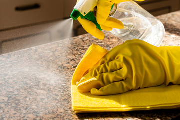 Man cleaning kitchen counter with solution to kill viruses and bacteria.