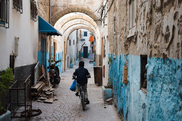 Niño solo en bicicleta por una calle estrecha en Marruecos