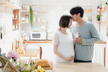 Asian pregnancy woman drinking milk from her husband. Couple, Motherhood, mom and kids, family relationship, new born baby, healthy pregnancy concept.