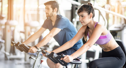Fototapeta na wymiar Young asian healthy woman bike cardio at the gym with smile and fresh face with her friend. Exercise, workout, muscle training, weight lifting, weight loss, heart rate practice and diet concept.