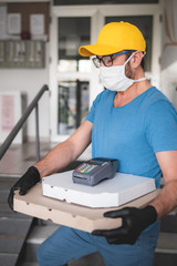Deliveryman with protective medical mask holding pizza box - days of viruses and pandemic, food...