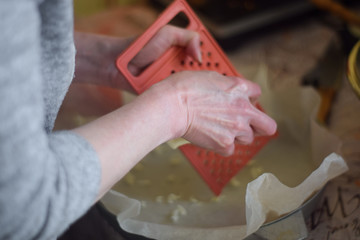 Woman rubs butter on a plastic grater close up