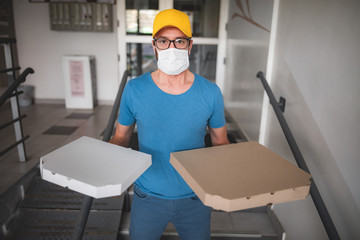 Deliveryman with protective medical mask holding pizza box - days of viruses and pandemic, food delivery to your home.