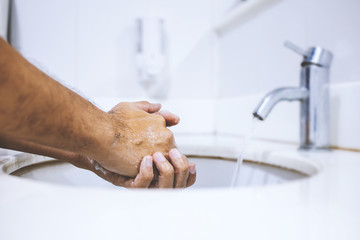 closeup image of washing hands rubbing with soap man for coronavirus (COVID-19) prevention. soft-focus and over light in the background