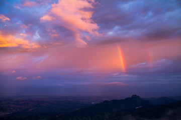 rainbow in colorful clouds over mountain