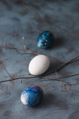 Background with Easter colorful eggs and branch on a blue surface.