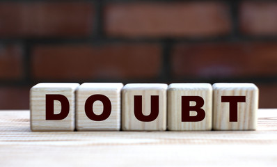 concept word DOUBT on cubes against the background of a brick wall