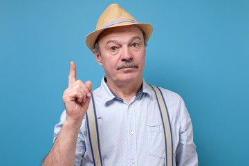 Elderly man in summer hat showing his finger up giving a good advice.