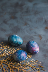 Happy Easter. Easter eggs with a golden branch on a blue surface.