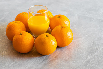 Sok pomarańczowy w szkle, dookoła świeże pomarańcze