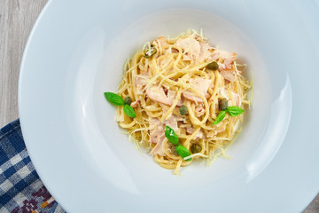 Appetizing homemade carbonara pasta with bacon, cream sauce and basil in a white plate. Close up, top view. Italian spaghetti, photo for the recipe