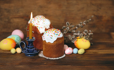 Easter holiday concept. Easter cakes, willow, eggs and candle on rustic wooden table. copy space.