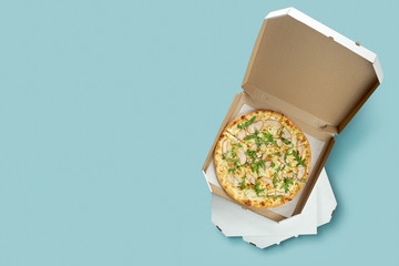 Conceptual poster for food and pizza delivery. Meat pizza in a cardboard box for delivery on a blue background with place for text