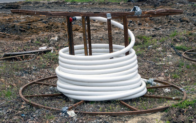 Coil of white industrial tubing at construction site.