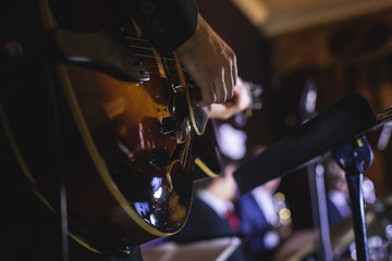 Concert view of an electric guitar player with vocalist and musical jazz band orchestra performing...