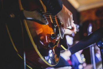 Concert view of an electric guitar player with vocalist and musical jazz band orchestra performing...