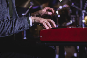 Concert view of a musical keyboard piano player during musical jazz band orchestra performing, keyboardist hands during concert, male pianist on the stage