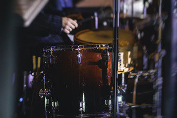 View of drum set kit on a stage during jazz rock show performance, with band performing in the background, drummer point of view