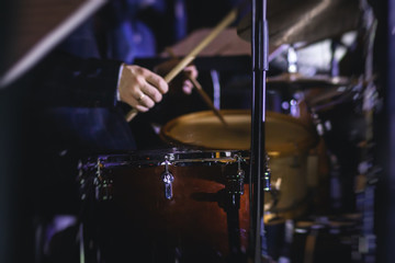 View of drum set kit on a stage during jazz rock show performance, with band performing in the...
