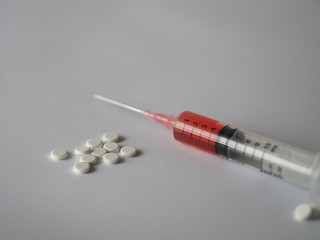 Pill Tablet and Hypodermic syringe with a sharp needle on white background