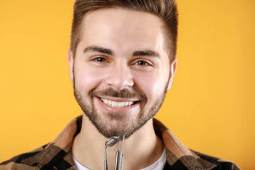 Obraz premium Happy smiling young man with dentist's tools on color background