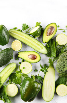 Green vegetables, fruits and herbs on a light background. Fresh pepper, zucchini, peas, cucumber, avocado, lime, broccoli, parsley, cilantro, dill and spinach. Foodbackground. Background image