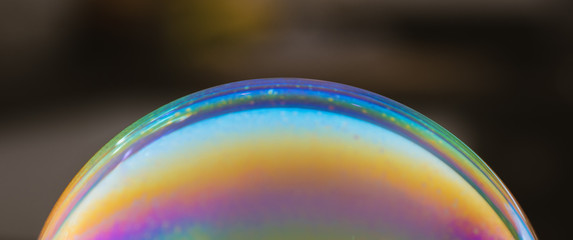 Soap bubble - colourful rainbow pattern on dark background - symbol of hope with copy space