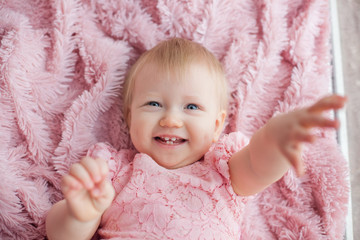 Portrait of a tender cute little baby girl lying down on a pink fluffy furry blanket, View from above, Baby photography concept