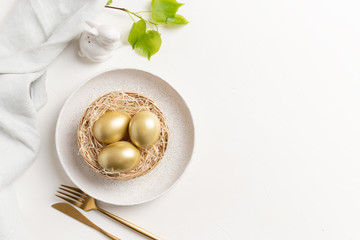 Easter table setting with bunny and golden eggs. Top view.